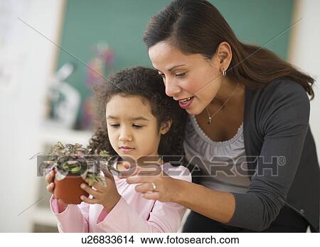 Picture - Girl (6-7) holding potted plant with female teacher. Fotosearch