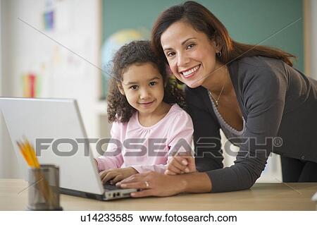 Girl (6-7) with female teacher using laptop in classroom View Large Photo Image Stock Photography - Girl (6-7) with female teacher using laptop in classroom. Fotosearch