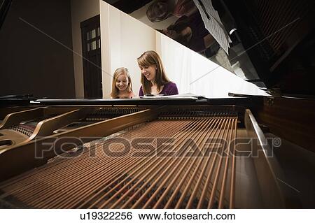 Stock Photograph - Girl (8-9) and mother playing grand piano . Fotosearch