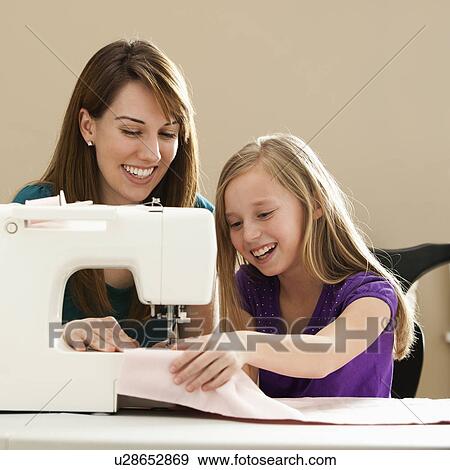 Stock Photo - Girl (8-9) and young woman using sewing machine. Fotosearch