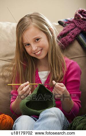 Stock Image - Girl (8-9) knitting woolly hat. Fotosearch