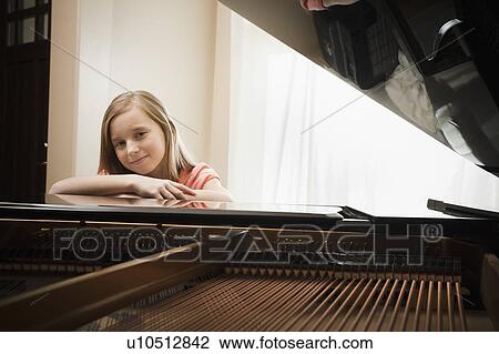 Girl (8-9) leaning on grand piano View Large Photo Image Stock Image - Girl (8-9) leaning on grand piano. Fotosearch