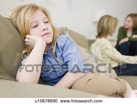Stock Image - Girl (8-9) sitting on sofa. Fotosearch