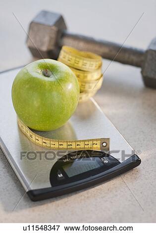 Green apple on weight scale, tape measure and exercise weight in background View Large Photo Image Stock Photo - Green apple on weight scale, tape measure and exercise weight in background. Fotosearch