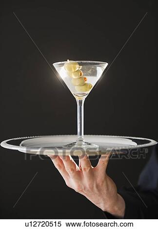 Stock Photography - Hand holding tray with martini. Fotosearch