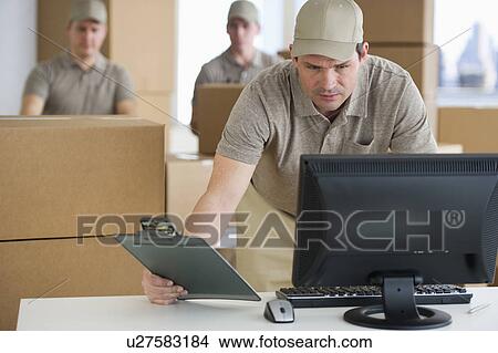 Picture - Man checking checklist in warehouse. Fotosearch