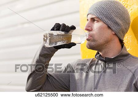 Stock Image - Man in workout wear drinking water. Fotosearch