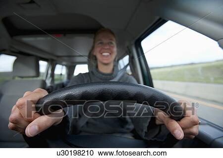 Stock Image - Mid adult woman driving. Fotosearch