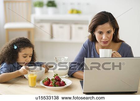 Stock Photo - Mother and daughter (6-7) during breakfast. Fotosearch