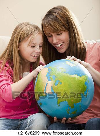 Stock Photo - Mother and daughter (8-9) playing with globe. Fotosearch