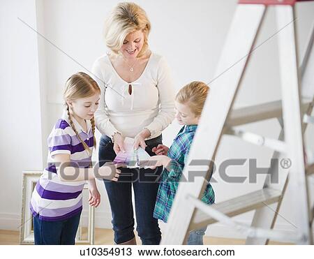 Stock Image - Mother and daughters (8-11) choosing color swatches. Fotosearch