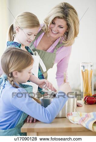 Stock Photo - Mother and daughters (8-11) cooking. Fotosearch