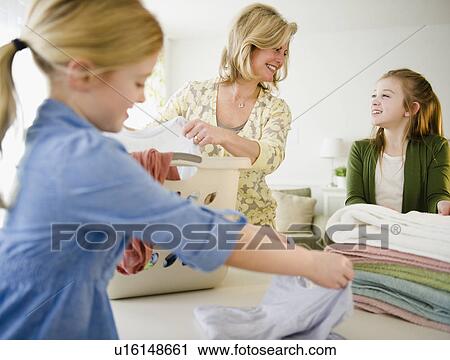 Stock Image - Mother and daughters (8-11) doing laundry. Fotosearch