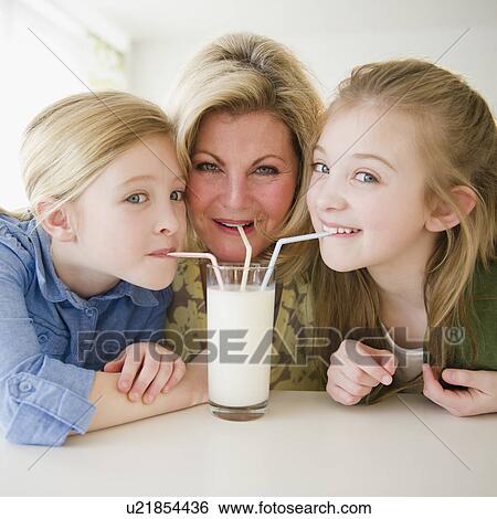 Stock Photograph - Mother and daughters (8-11) drinking milk through straws. Fotosearch