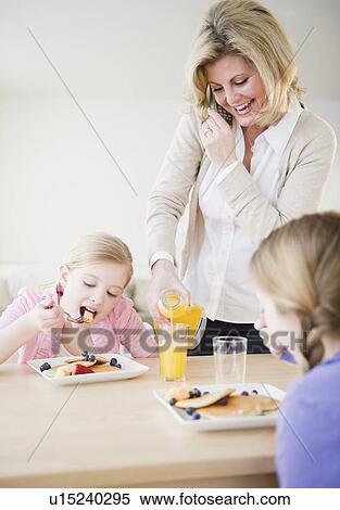 Stock Photography - Mother and daughters (8-11) eating breakfast. Fotosearch