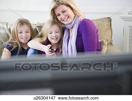 Stock Photo - Mother and daughters (8-11) watching tv. Fotosearch