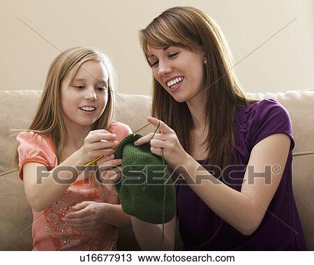 Stock Image - Mother giving daughter (8-9) knitting tips. Fotosearch