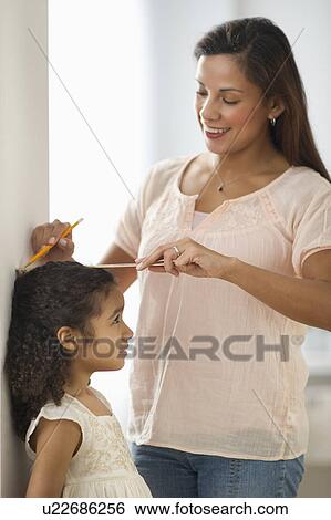 Stock Photograph - Mother measuring daughter (6-7) . Fotosearch