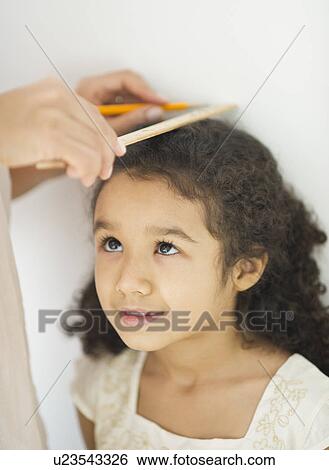 Stock Photograph - Mother measuring daughter (6-7) . Fotosearch