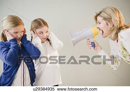 Stock Photography - Mother shouting at daughters (8-11) through bullhorn. Fotosearch