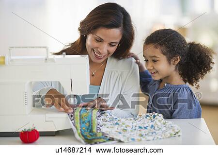 Picture - Mother with daughter (6-7) using sewing machine. Fotosearch