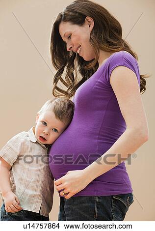 Picture - Portrait of boy (2-3) leaning pregnant mother's belly. Fotosearch