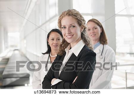 Portrait of businesswoman with doctors in background View Large Photo Image Stock Image - Portrait of businesswoman with doctors in background. Fotosearch