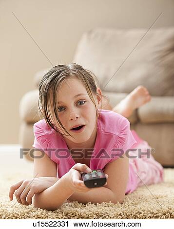 Portrait of girl (10-11) lying on floor holding remote control View Large Photo Image Stock Image - Portrait of girl (10-11) lying on floor holding remote control. Fotosearch
