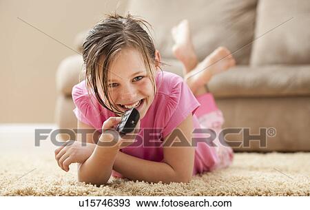 Portrait of girl (10-11) lying on floor holding remote control View Large Photo Image Stock Image - Portrait of girl (10-11) lying on floor holding remote control. Fotosearch