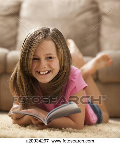 Stock Photo - Portrait of girl (10-11) lying on rug with book. Fotosearch