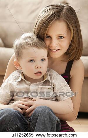 Portrait of Girl (10-11) with brother (2-3) sitting on floor View Large Photo Image Stock Photography - Portrait of Girl (10-11) with brother (2-3) sitting on floor. Fotosearch