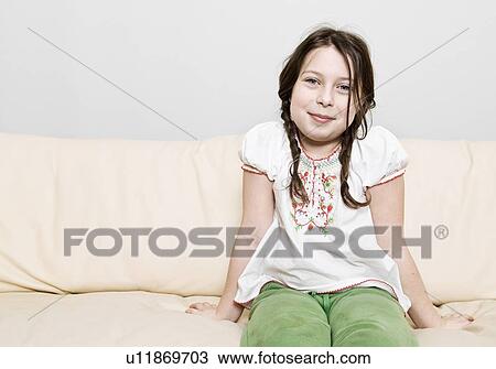 Portrait of girl (8-9) sitting on sofa View Large Photo Image Stock Image - Portrait of girl (8-9) sitting on sofa. Fotosearch