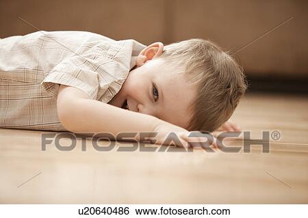 Portrait of smiling boy (2-3) lying on floor View Large Photo Image Stock Photograph - Portrait of smiling boy (2-3) lying on floor. Fotosearch
