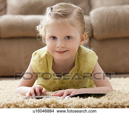 Picture - Portrait of smiling girl (2-3) lying on rug with book. Fotosearch