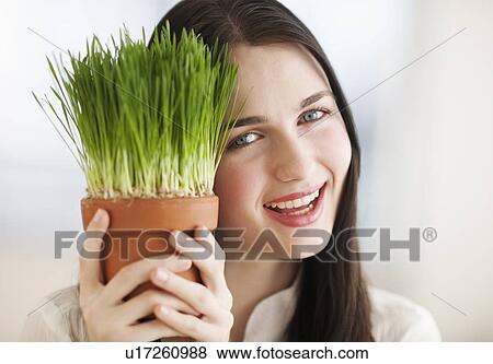 Portrait of smiling young woman holding green plant View Large Photo Image Stock Photo - Portrait of smiling young woman holding green plant. Fotosearch