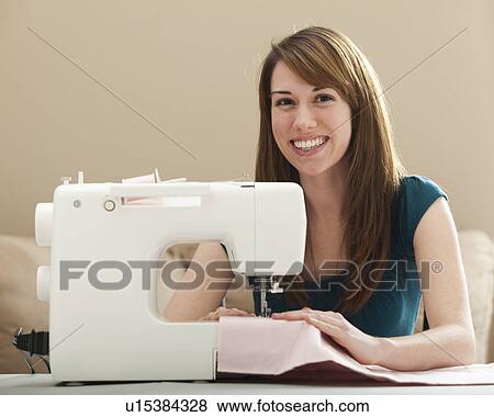Stock Photo - Portrait of smiling young woman using sewing machine. Fotosearch