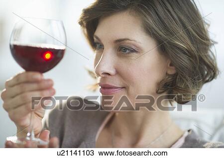 Stock Image - Portrait of woman holding glass of red wine. Fotosearch
