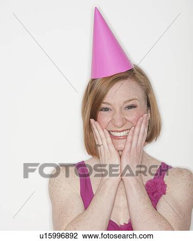 Stock Image - Portrait of woman wearing pink party hat. Fotosearch