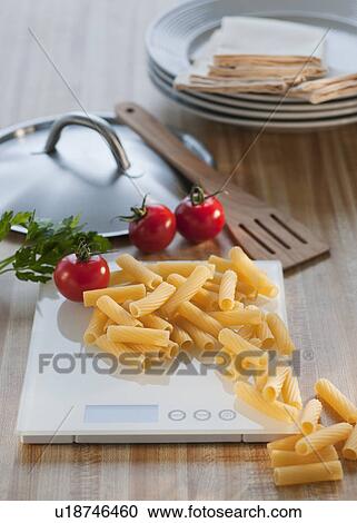 Stock Image - Raw pasta on weight scale. Fotosearch