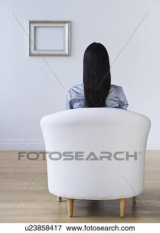Rear view of woman sitting in armchair View Large Photo Image Stock Photo - Rear view of woman sitting in armchair. Fotosearch