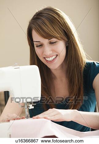 Smiling young woman using sewing machine View Large Photo Image Stock Photo - Smiling young woman using sewing machine. Fotosearch