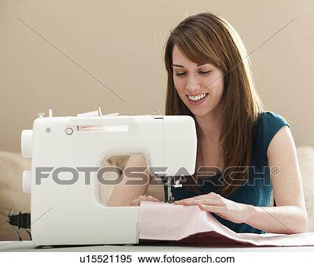 Stock Photography - Smiling young woman using sewing machine. Fotosearch
