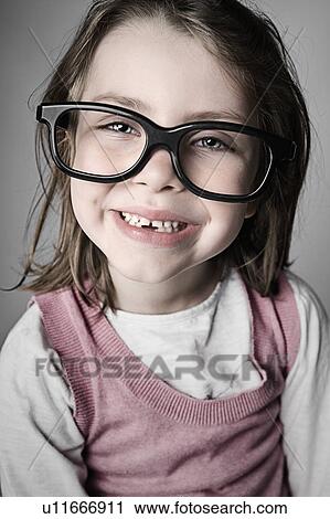 Stock Image - Studio portrait of girl (6-7) wearing big glasses. Fotosearch
