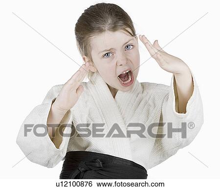 Stock Photograph - Studio portrait of girl (6-7) wearing karate uniform. Fotosearch