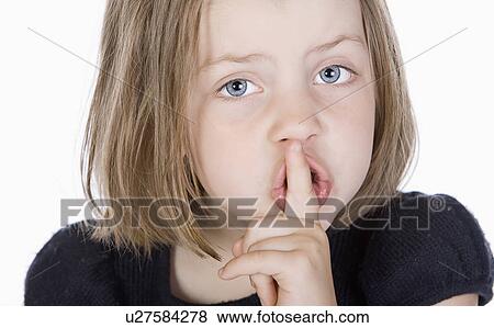 Stock Photo - Studio portrait of girl (6-7) with finger on lips. Fotosearch