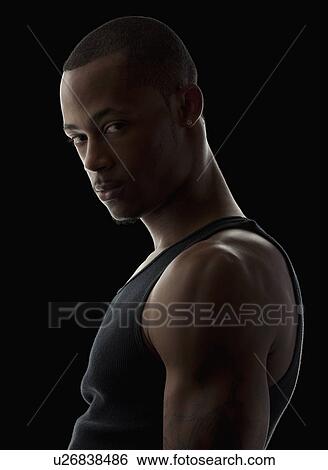 Stock Photograph - Studio portrait of muscular young man wearing tank top. Fotosearch