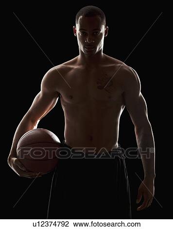 Stock Image - Studio portrait of shirtless man holding basketball. Fotosearch