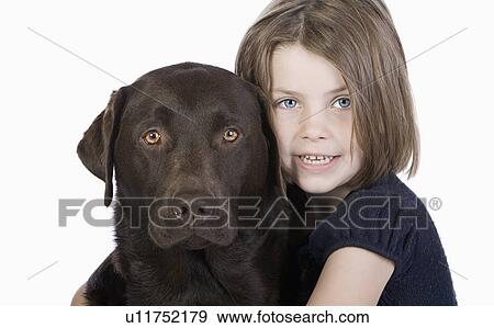 Studio portrait of smiling girl (6-7) hugging chocolate labrador View Large Photo Image Stock Photo - Studio portrait of smiling girl (6-7) hugging chocolate labrador. Fotosearch