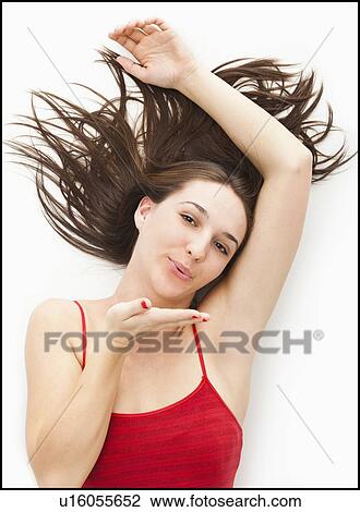 Stock Image - Studio portrait of young woman blowing a kiss. Fotosearch