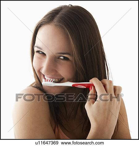 Stock Photo - Studio portrait of young woman brushing teeth. Fotosearch